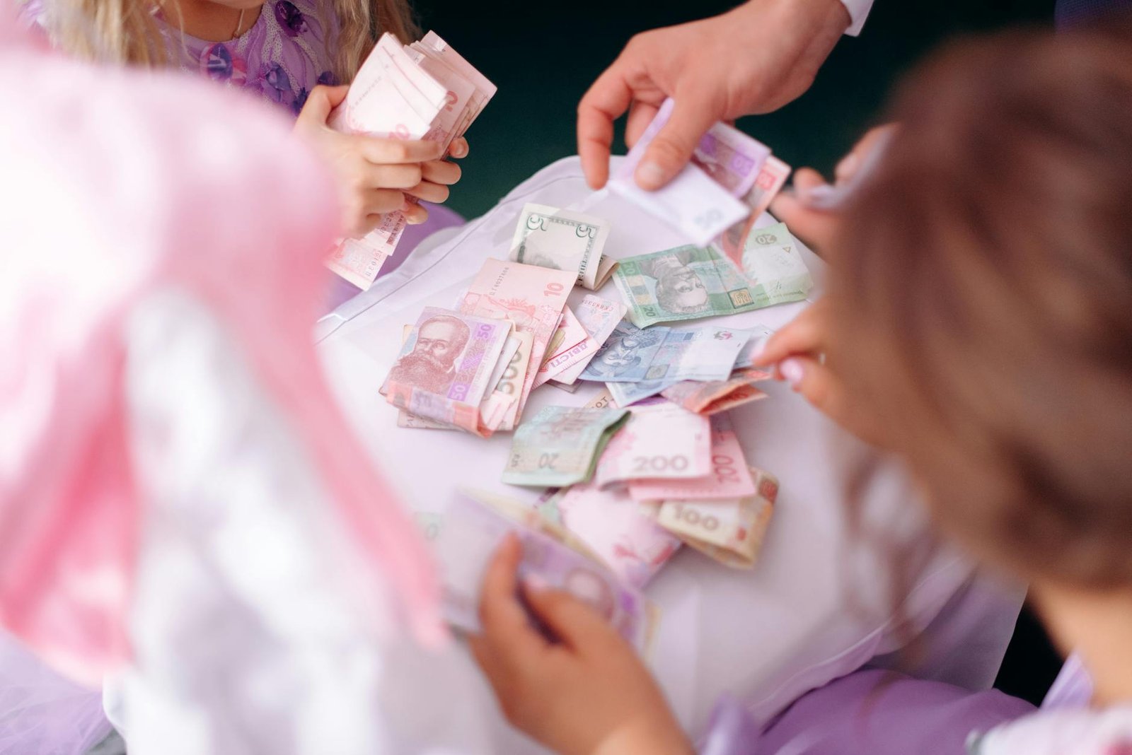 "Adult and child hands sorting colorful banknotes, representing financial education and debt management."