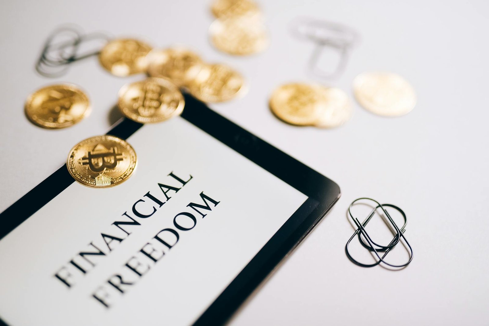 Close-up of Bitcoin coins and iPad showing 'Financial Freedom,' representing modern financial independence.