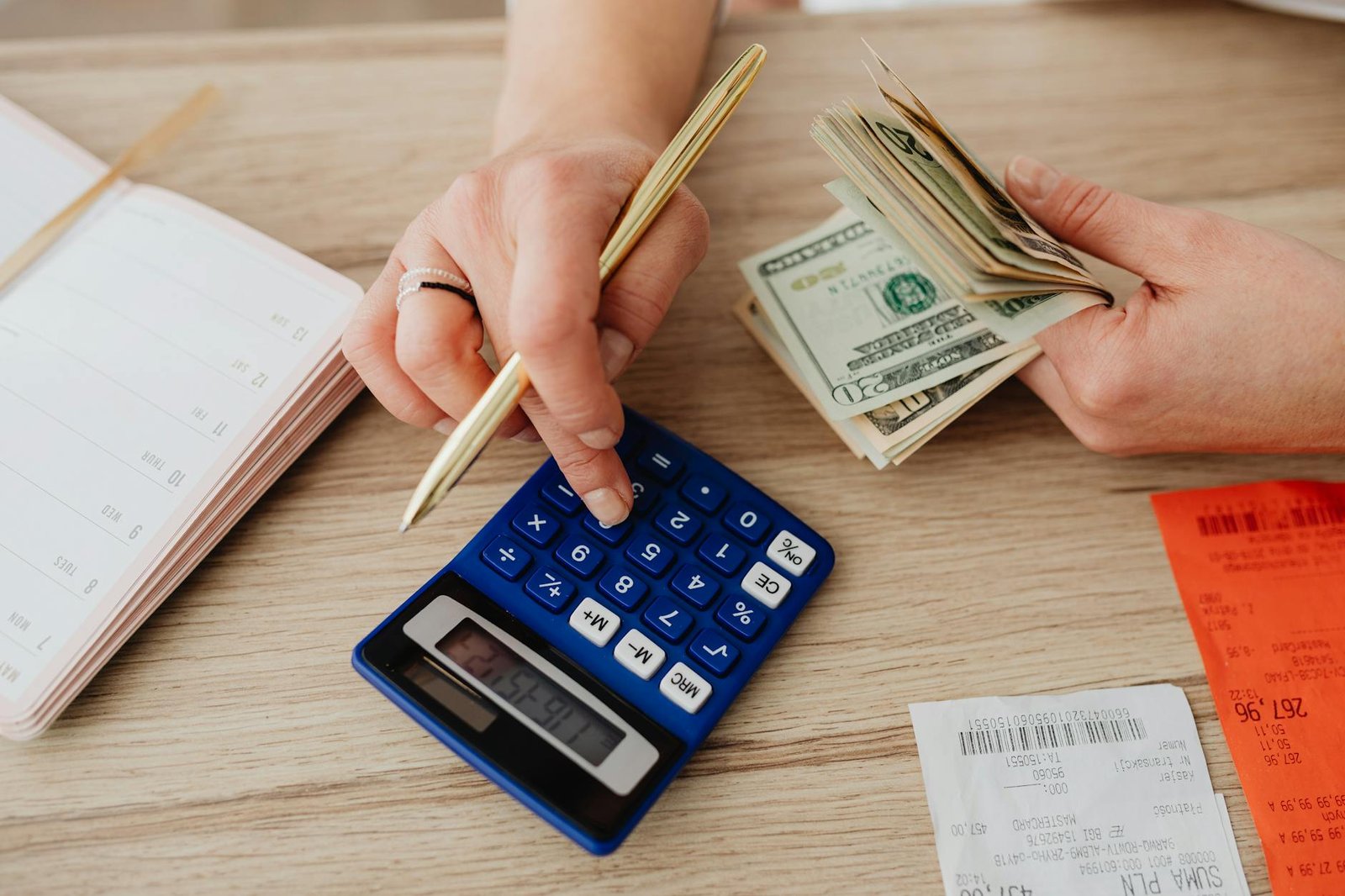 Hands calculating cash with a calculator for effective monthly budget planning.